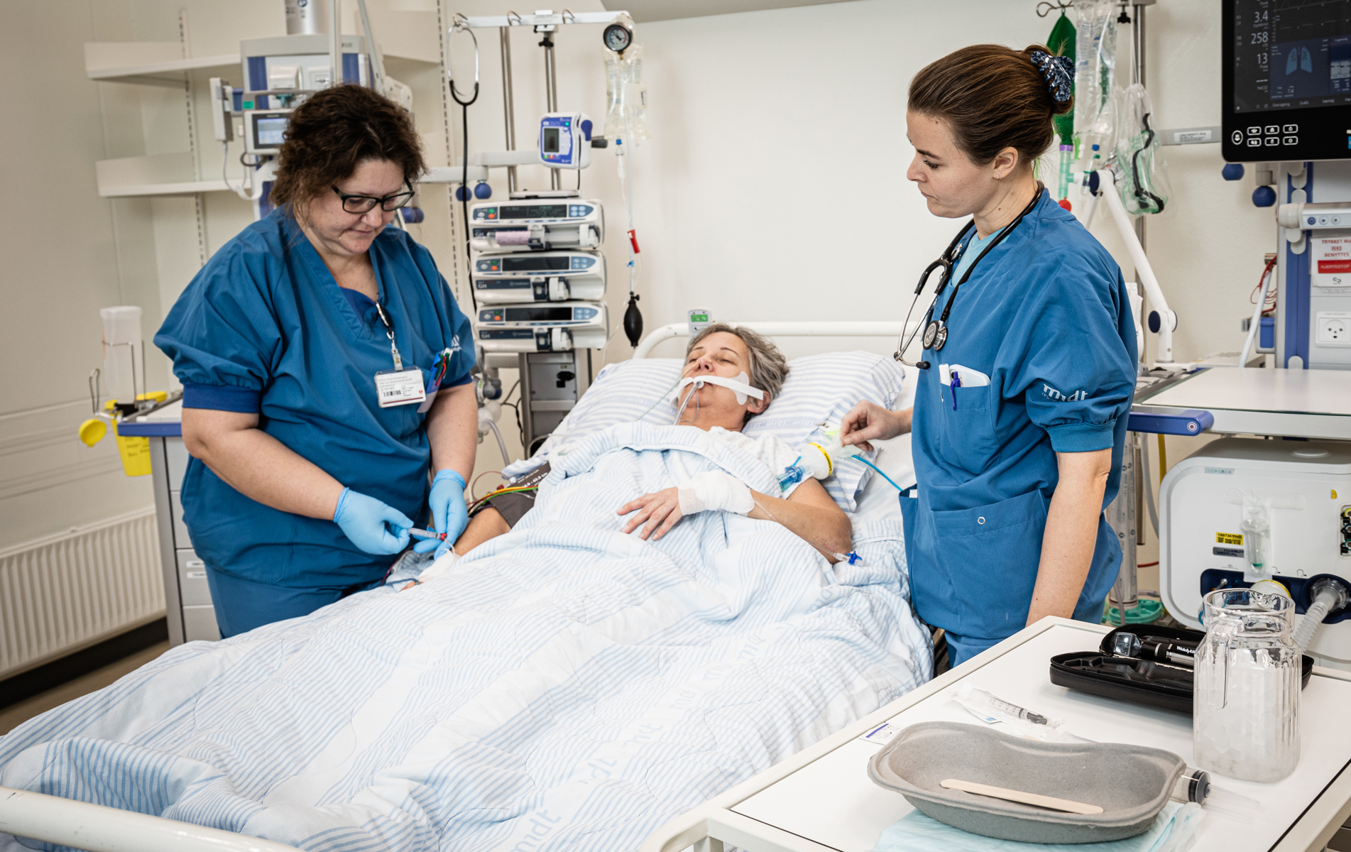 En læge og en sygepl. behandler en intensivpatient